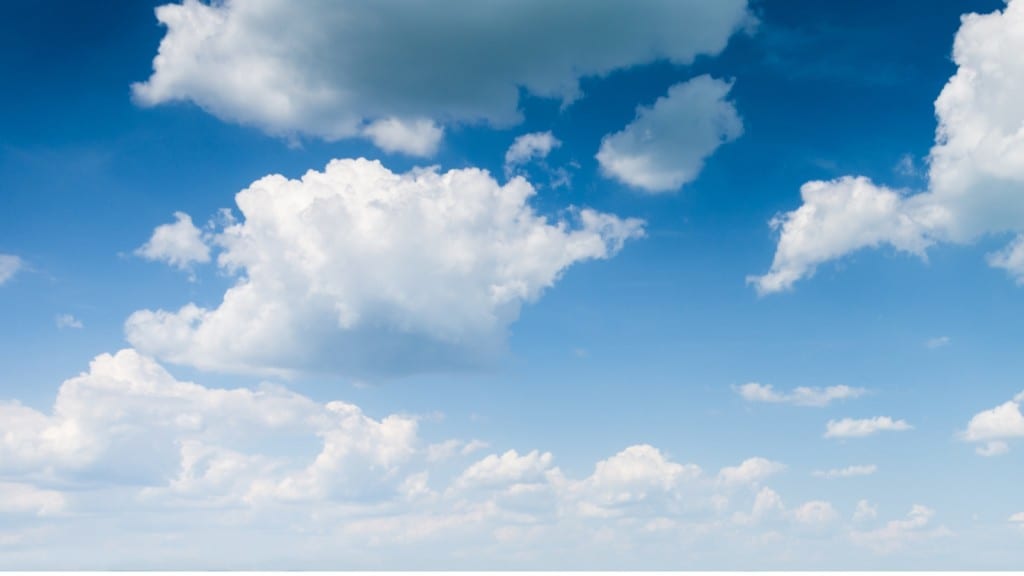 Fluffy white clouds scattered across a bright blue sky.