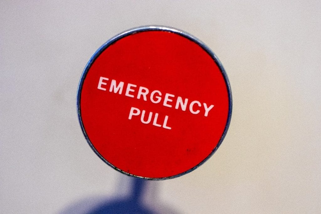 Red emergency pull sign against a clear sky.